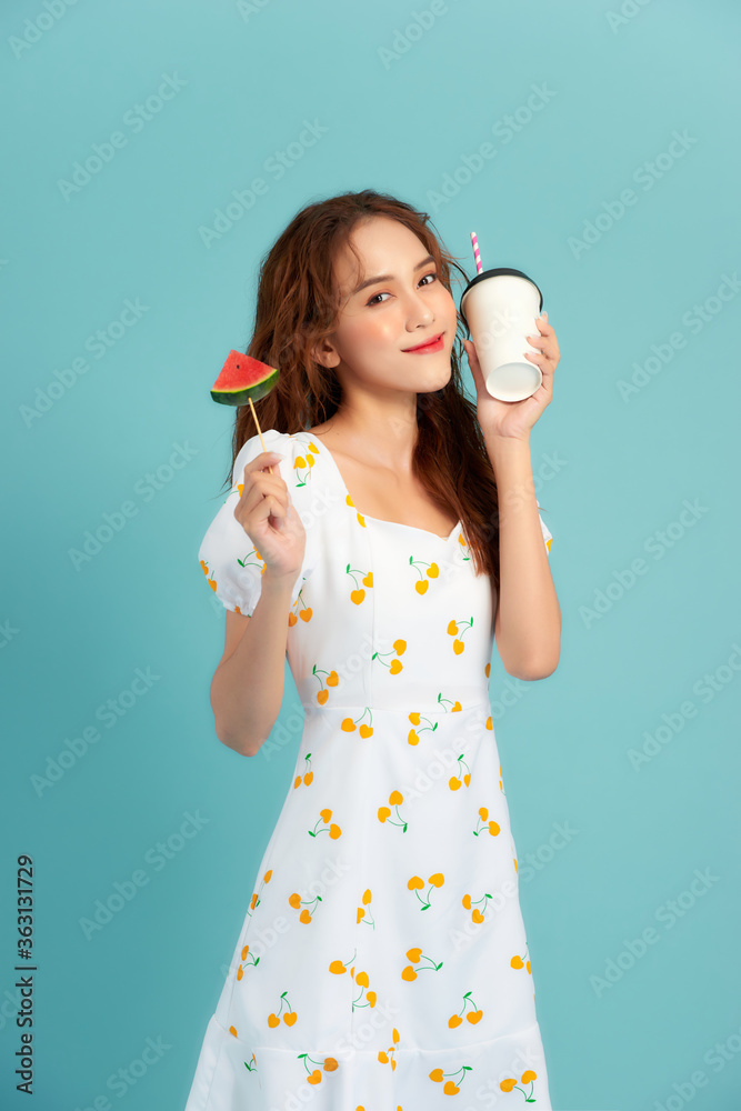 时尚写真漂亮酷女孩喝杯子里的果汁，手里拿着西瓜片