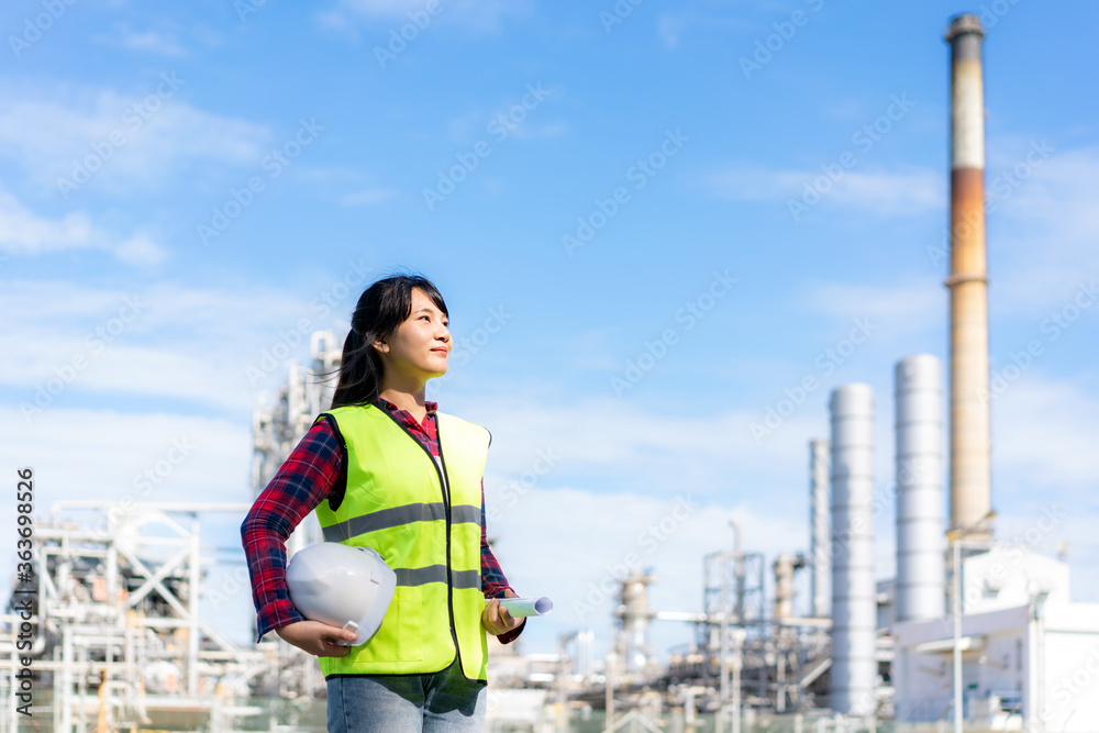 亚洲女工程师戴着白色安全帽，用石油展望未来