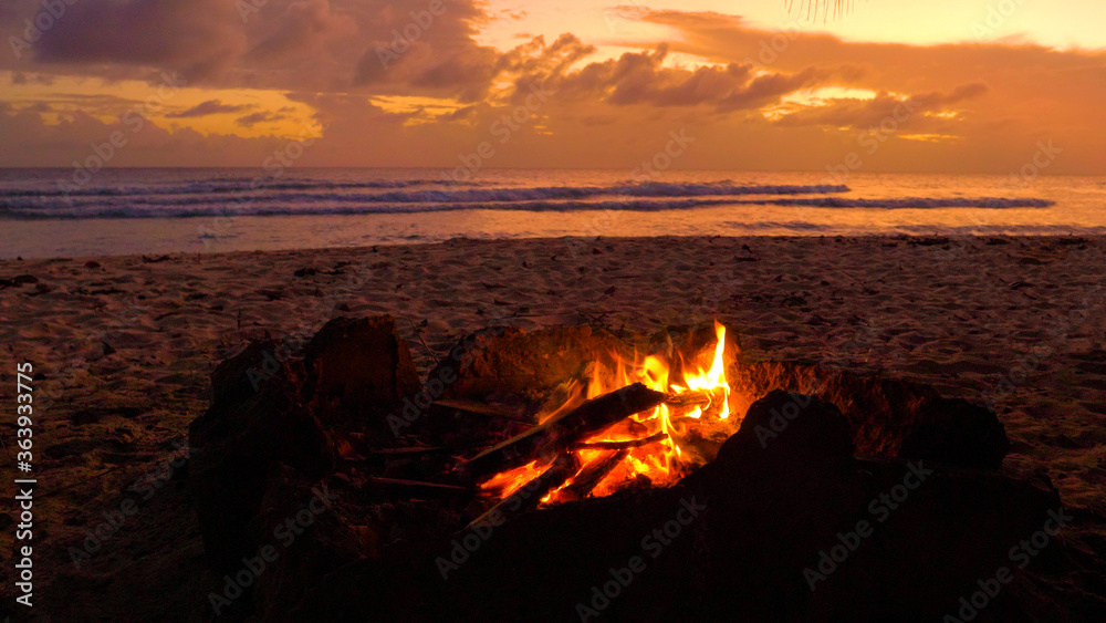 特写：日落时分，沙滩上的一个壁炉里燃起了小火。