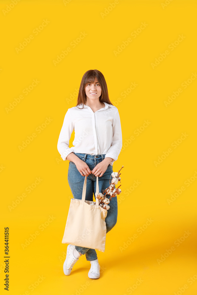 漂亮的年轻女人，带着棉花花和彩色背景的购物袋