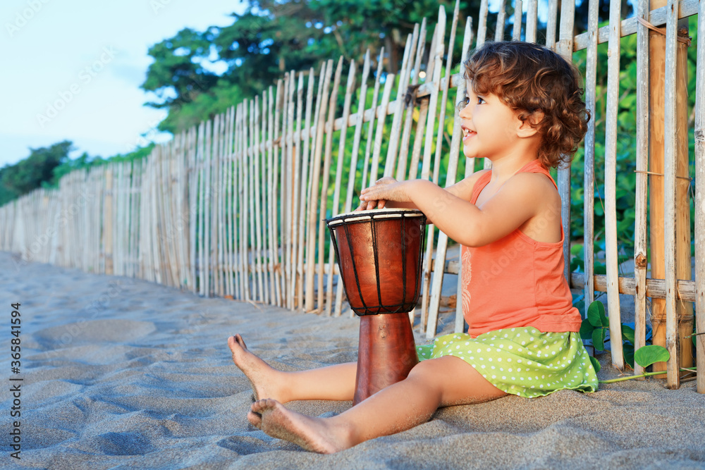 快乐的小宝贝女孩用传统的非洲手鼓djembe演奏民族音乐，享受日落
