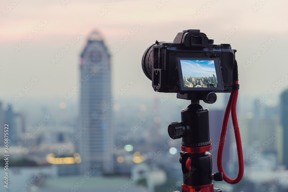 三脚架特写相机拍摄日落城市景观，背景是城市市中心的城市旅行理念