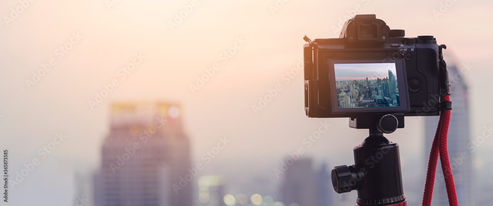 三脚架特写相机拍摄日落城市景观，背景是城市市中心的城市旅行理念