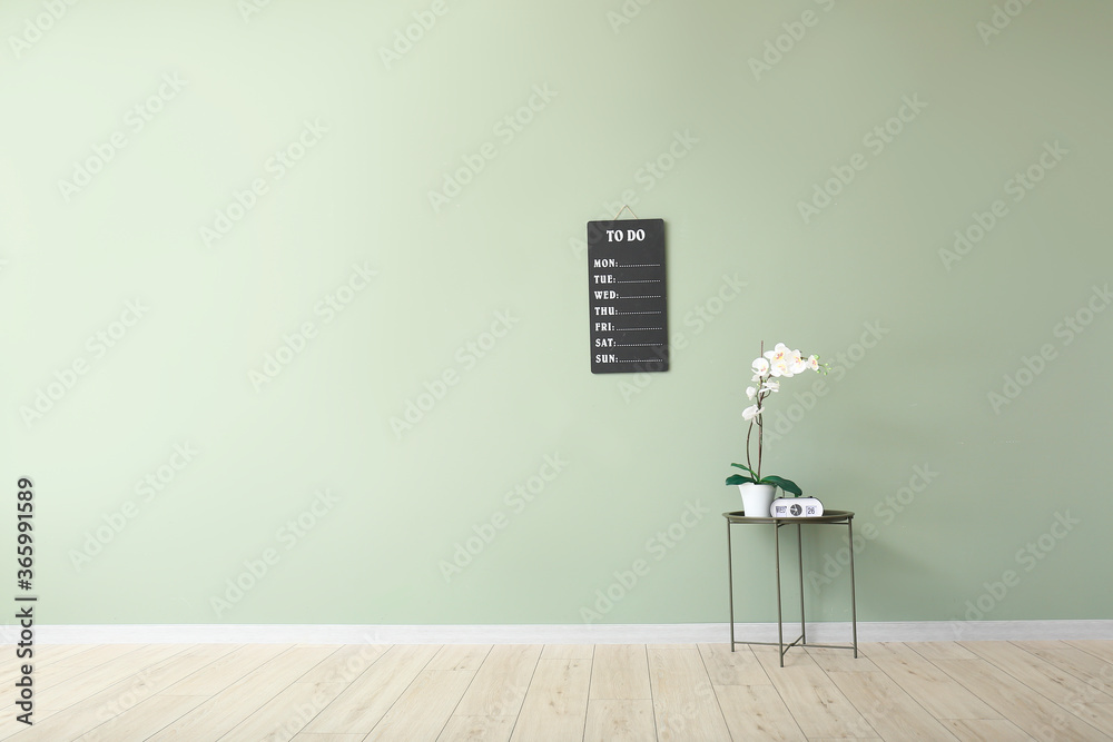房间彩色墙上有闹钟和室内植物的桌子