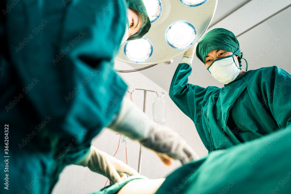 在现代手术室进行外科手术的专业医疗团队。亚洲助理广告