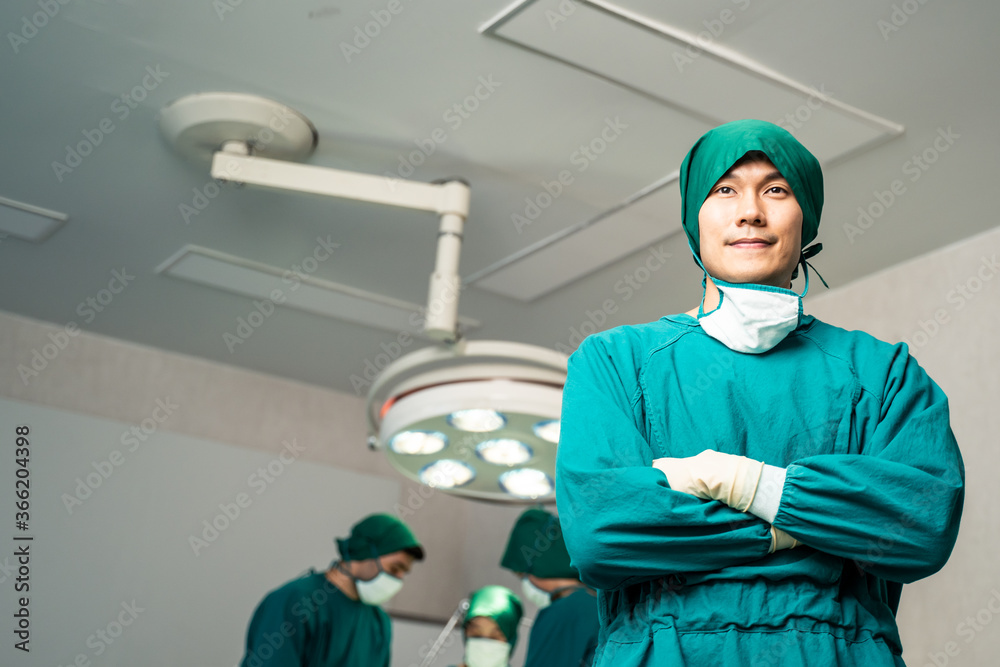 专业外科医生亚洲男子站在前面的肖像。团队正在进行外科手术