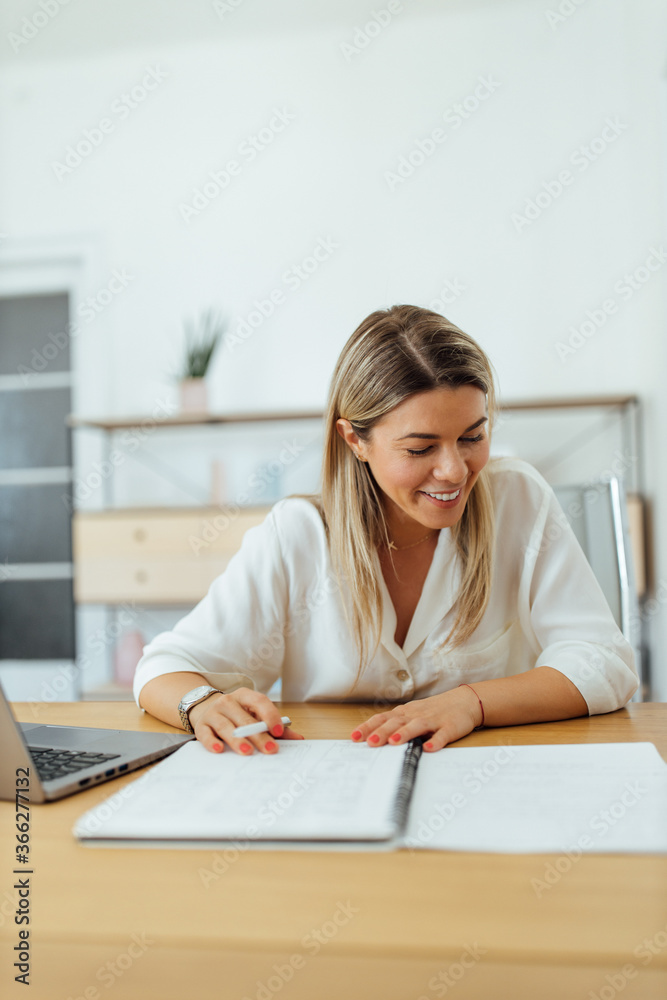 一位微笑的女商人阅读文件的肖像。
