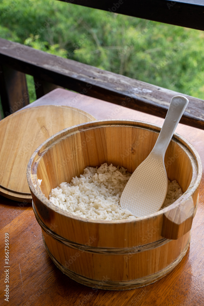 Delicious cooked plain rice in a big wooden bowl ready-to-eat with white rice spatula spoon at resta