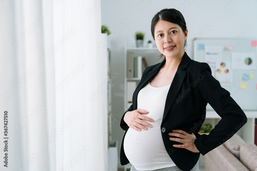 自信的孕妇穿着西装在现代办公室工作。优雅的年轻大肚子未来妈妈