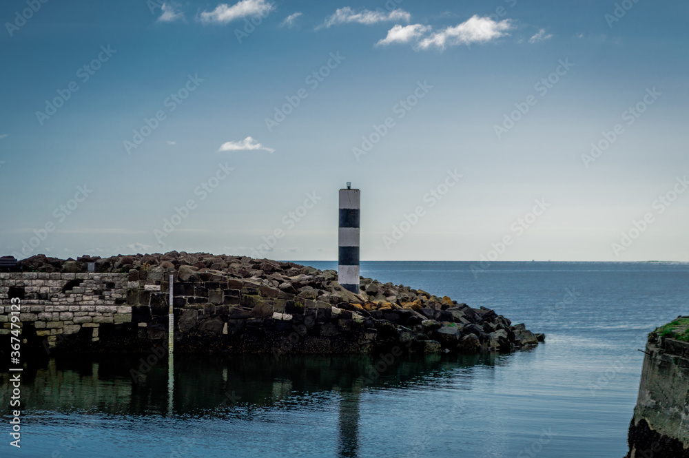 一座孤独的灯塔守卫着岩石港口，眺望着北爱尔兰的大海。