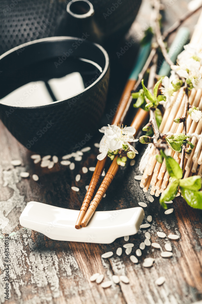 乡村木桌上的中式茶具、筷子和樱花枝