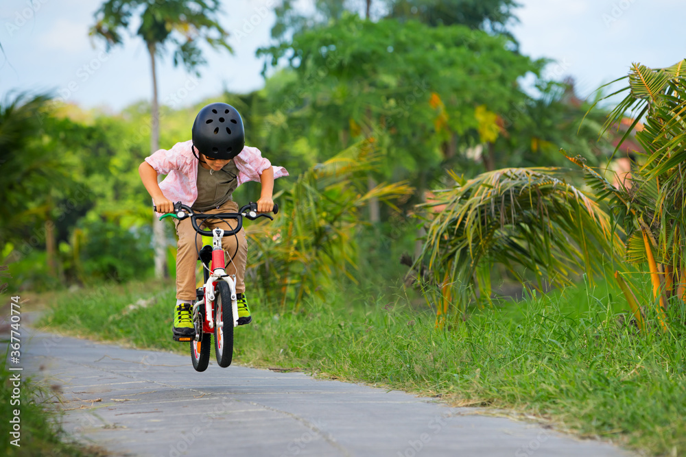 乡村自行车散步。戴着头盔和太阳镜的年轻骑手骑自行车。快乐的孩子玩得开心
