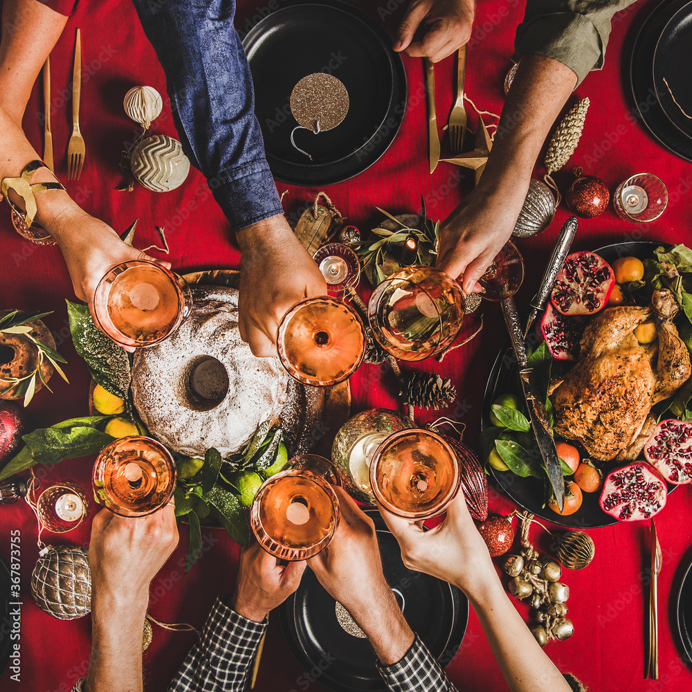 Friends celebrating Christmas. Flat-lay of people clinking glasses with rose wine over festive table