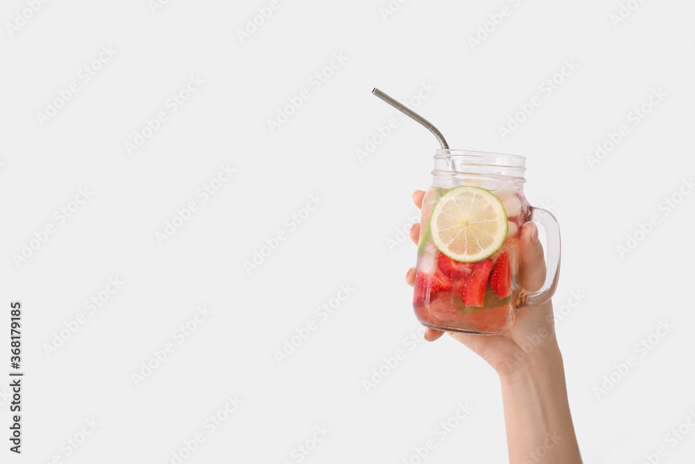 手拿一罐淡背景的新鲜草莓柠檬水