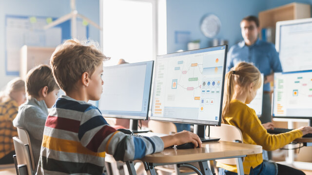 小学计算机科学课堂:聪明的小男孩在个人电脑上工作，Lea