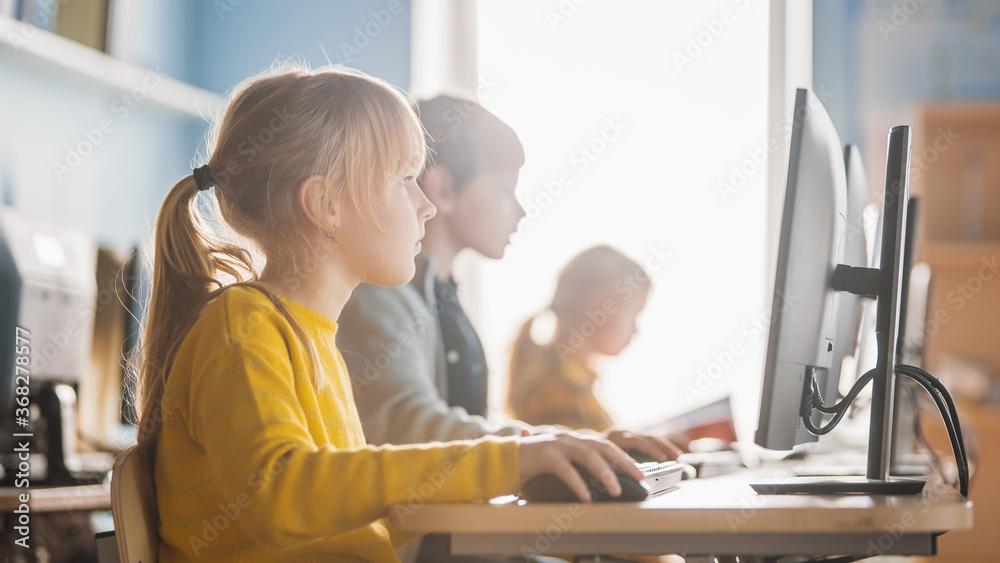 小学计算机科学教室：一个聪明可爱的女孩使用个人电脑的画像
