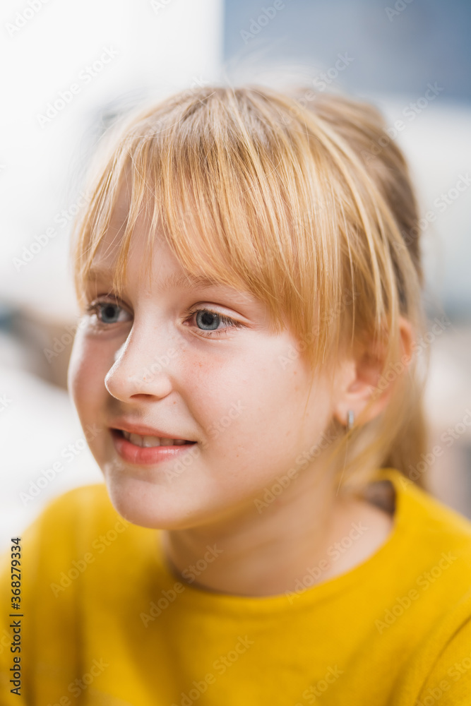 一个金发可爱的小女孩坐在学校的桌子旁，笑得很开心。聪明的Lit
