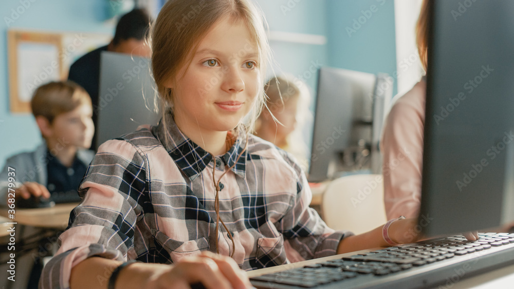 小学计算机科学课堂：聪明可爱女孩使用个人电脑的画像