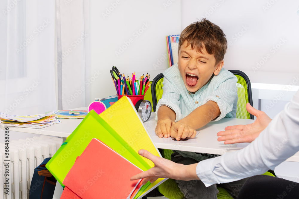 患有自闭症谱系障碍的男孩以负面表达行为将课本和书籍从桌子上扔下来