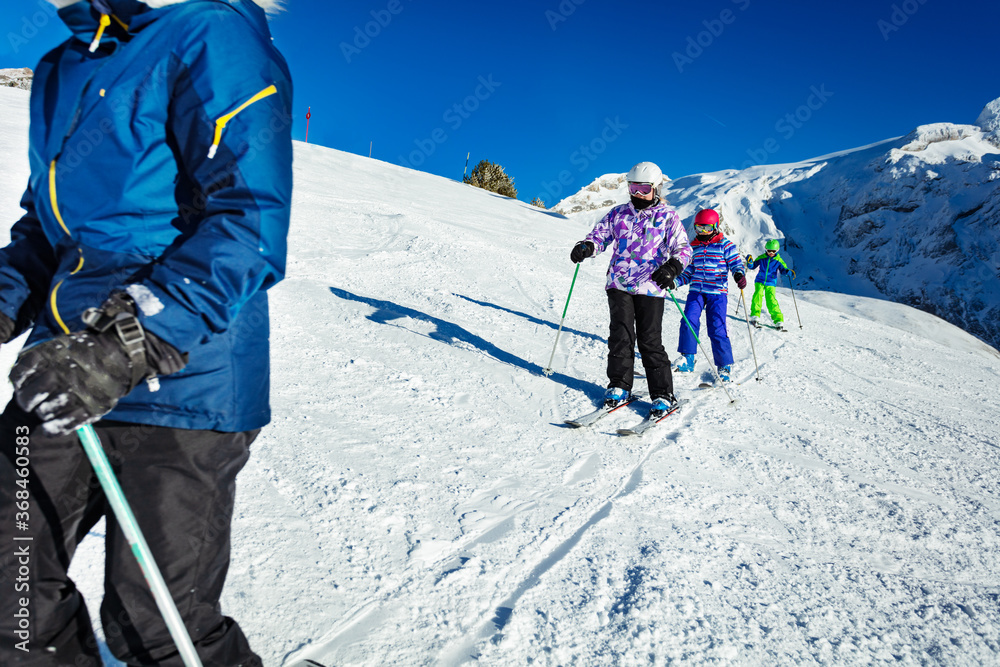三个孩子作为学校小组的一员在阿尔卑斯山的斜坡上滑雪，一个接一个地在山上滑雪