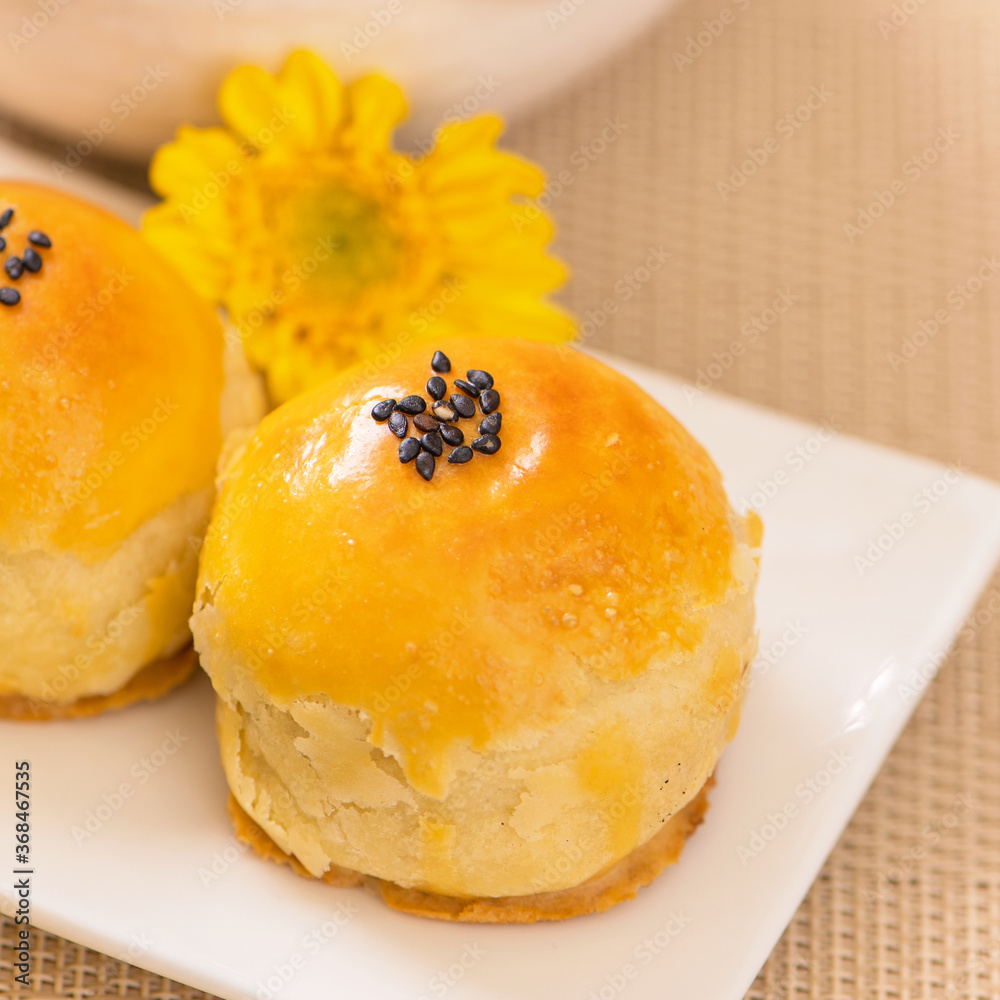 Tasty baked egg yolk pastry moon cake for Mid-Autumn Festival on bright wooden table background. Chi
