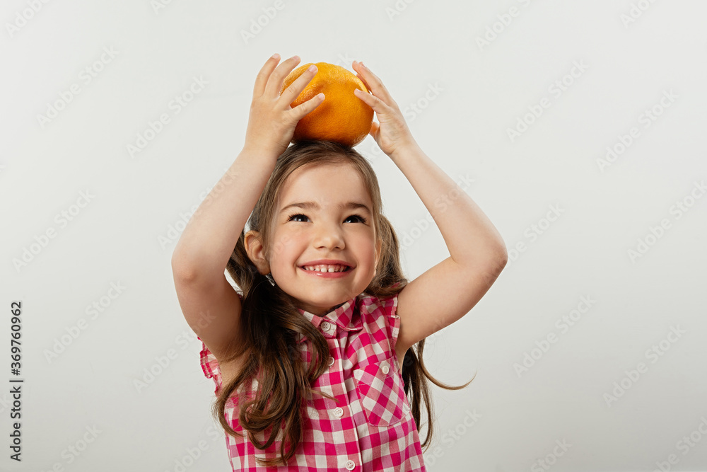 可爱快乐的小女孩在玩鲜艳多汁的橙子