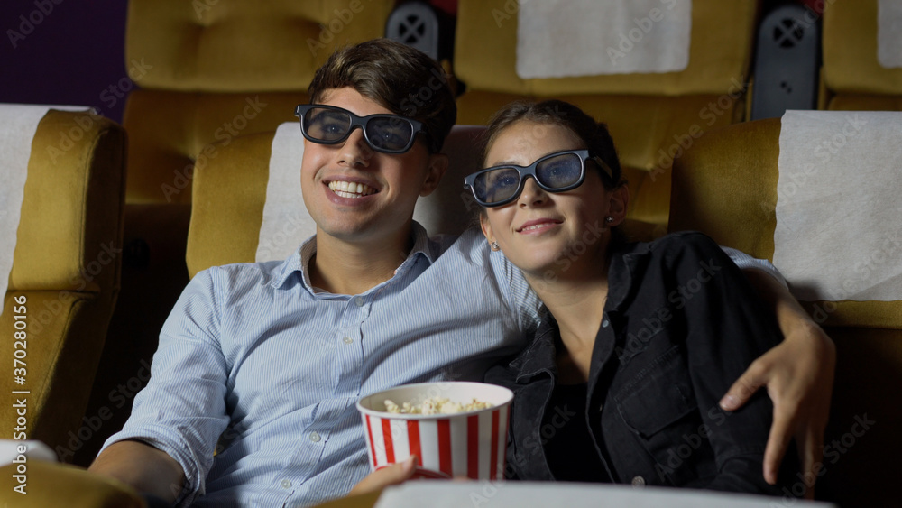 Man and woman in the cinema watching a movie with 3D glasses. with interest looking at the screen, e