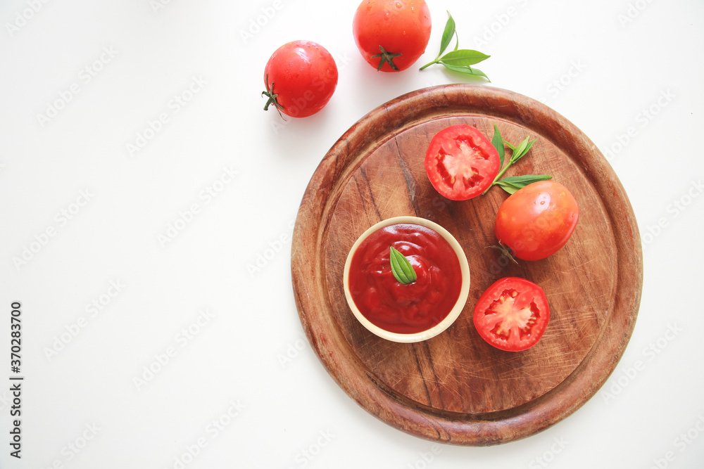 Bowl of ketchup or tomatoes sauce with ingredients on wooden plate.