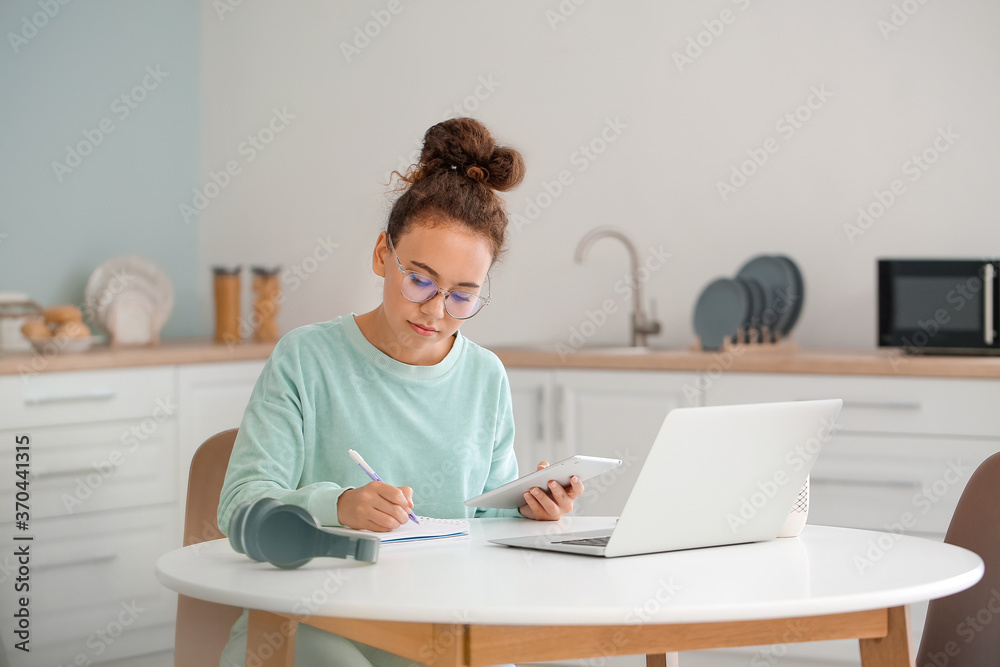 年轻女性在家使用平板电脑和笔记本电脑进行在线学习