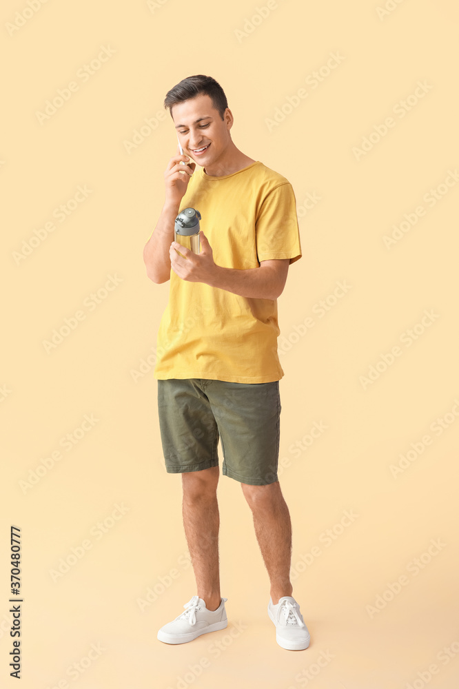 年轻人拿着一瓶水在彩色背景下通过电话交谈