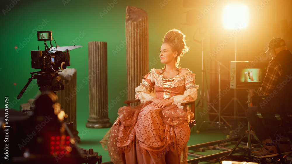 时代服装戏剧电影片场：美丽微笑的女演员穿着文艺复兴时期的连衣裙，坐在椅子上