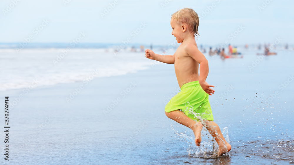 快乐的一家人在热带海滩度假胜地玩得很开心。有趣的男婴在水池边溅水奔跑