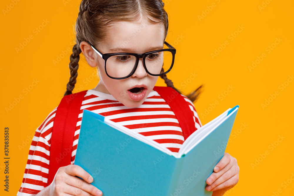 Astonished schoolgirl reading textbook during studies.