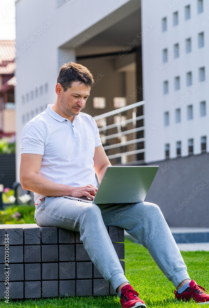 一个男人在笔记本电脑前的肖像。在大楼附近的户外摆姿势。