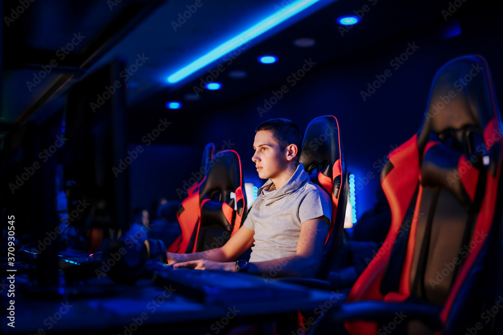 年轻玩家在网吧或游戏室玩电子游戏，肖像，侧视图。