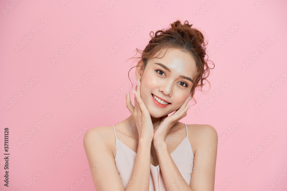 年轻可爱的亚洲女人在粉色背景下微笑的肖像。