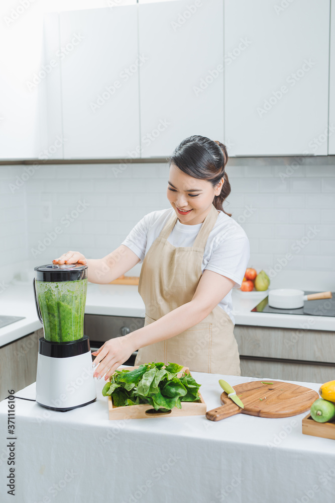 Vegetable smoothie woman blending green smoothies with blender home in kitchen