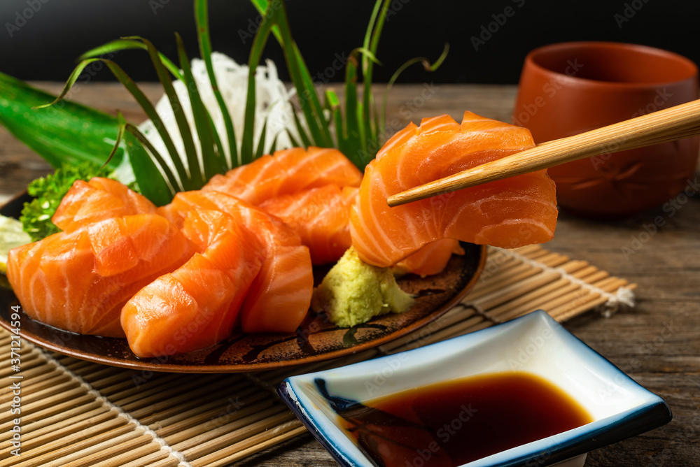 木桌上的刺身、三文鱼、日式筷子和芥末