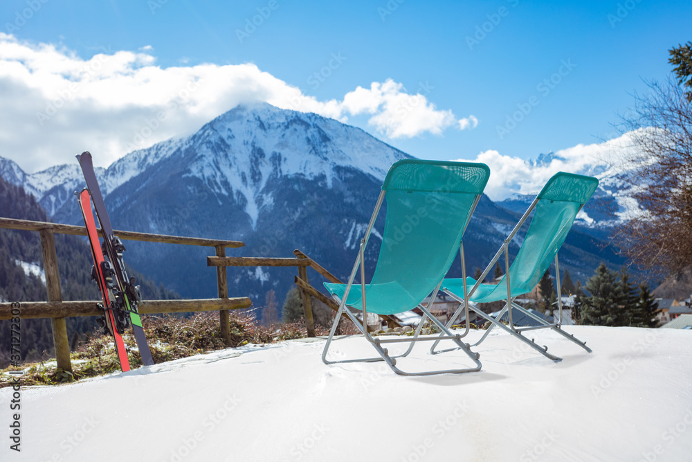 冬季滑雪场山景上的两副滑雪板和躺椅
