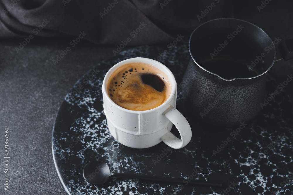 一杯黑底带壶的热咖啡