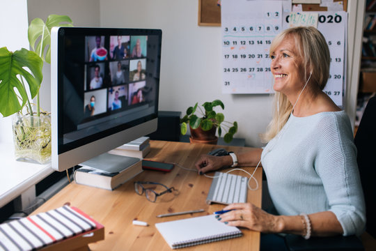 Smiling mature woman having video call via computer in the home office. Online team meeting video co