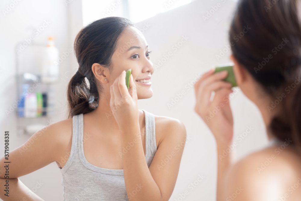 亚洲女人在浴室里把芦荟涂在脸上。