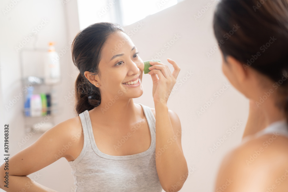 亚洲女人在浴室里把芦荟涂在脸上。