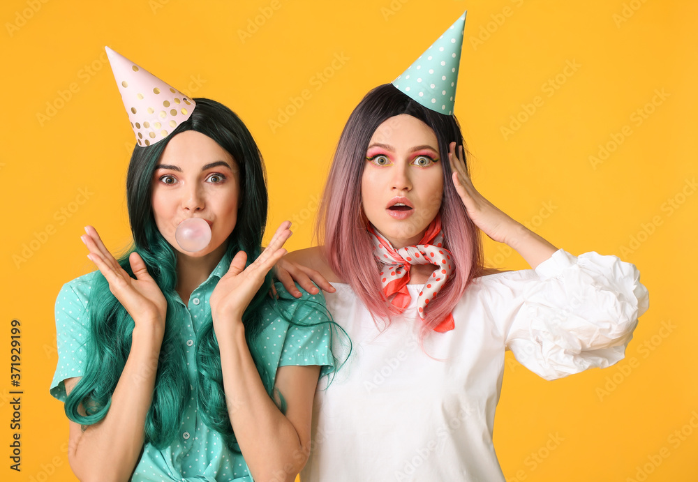 Beautiful young women in party wigs on color background