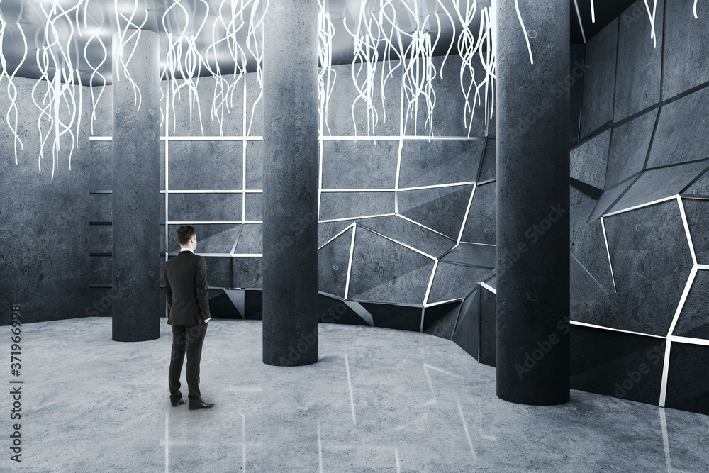 Businessman standing in gallery interior with  concrete columns.