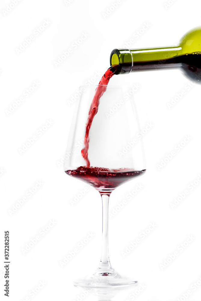 一瓶红葡萄酒和酒杯在白底上隔离。奢华的法国葡萄酒倒在玻璃杯里。