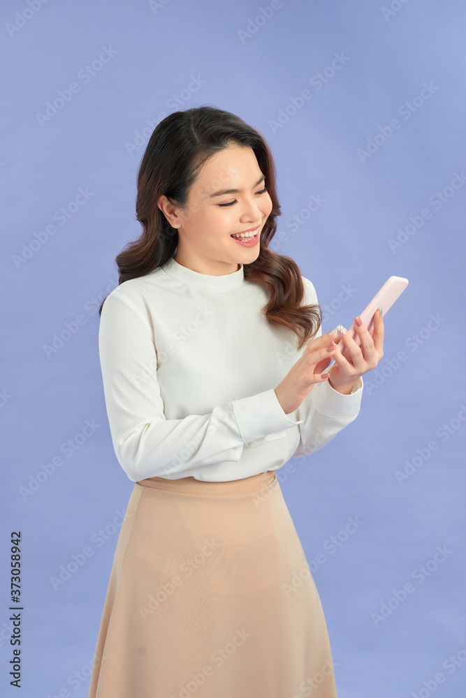 紫色背景下，开朗的女商人微笑着使用手机的照片