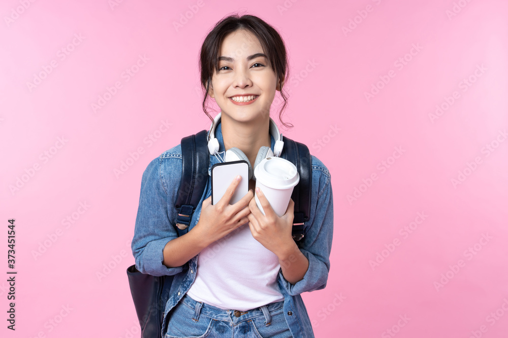 年轻的亚洲女学生拿着智能手机咖啡和背包站着的肖像。大学少年