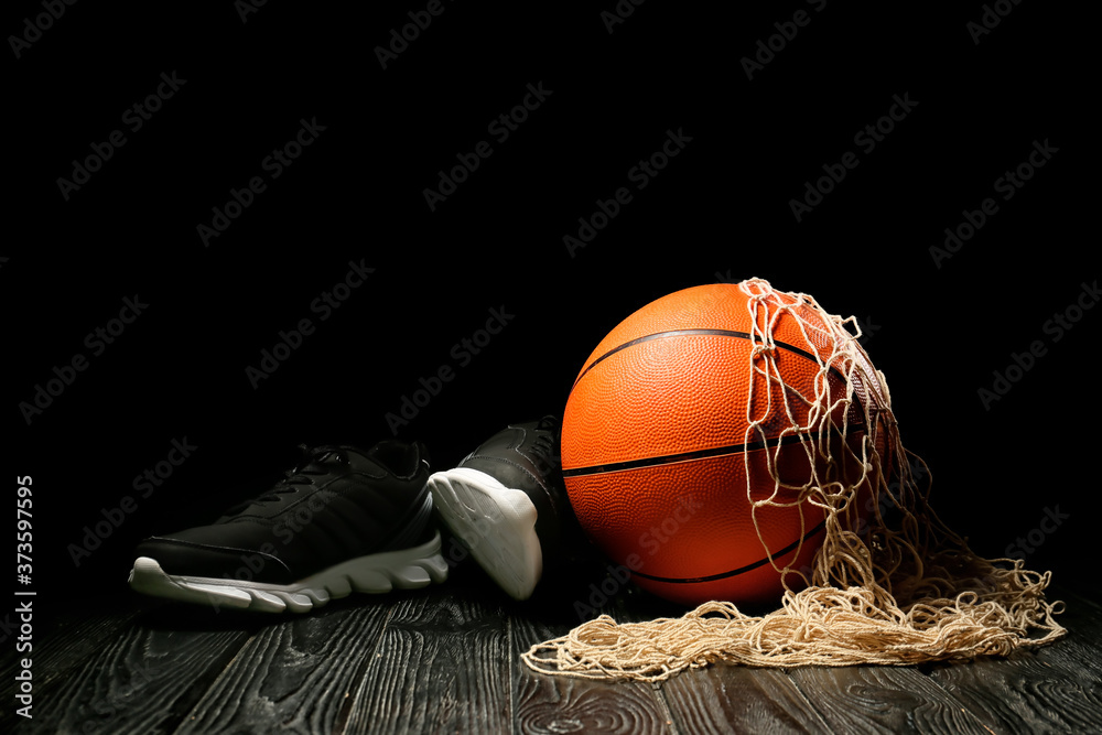 在深色背景下，桌子上的篮球、鞋子和球网