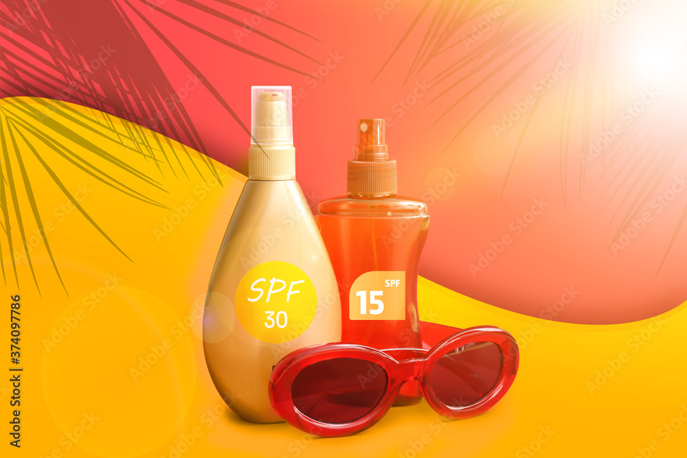 Bottles of sunscreen cream with sunglasses on color background